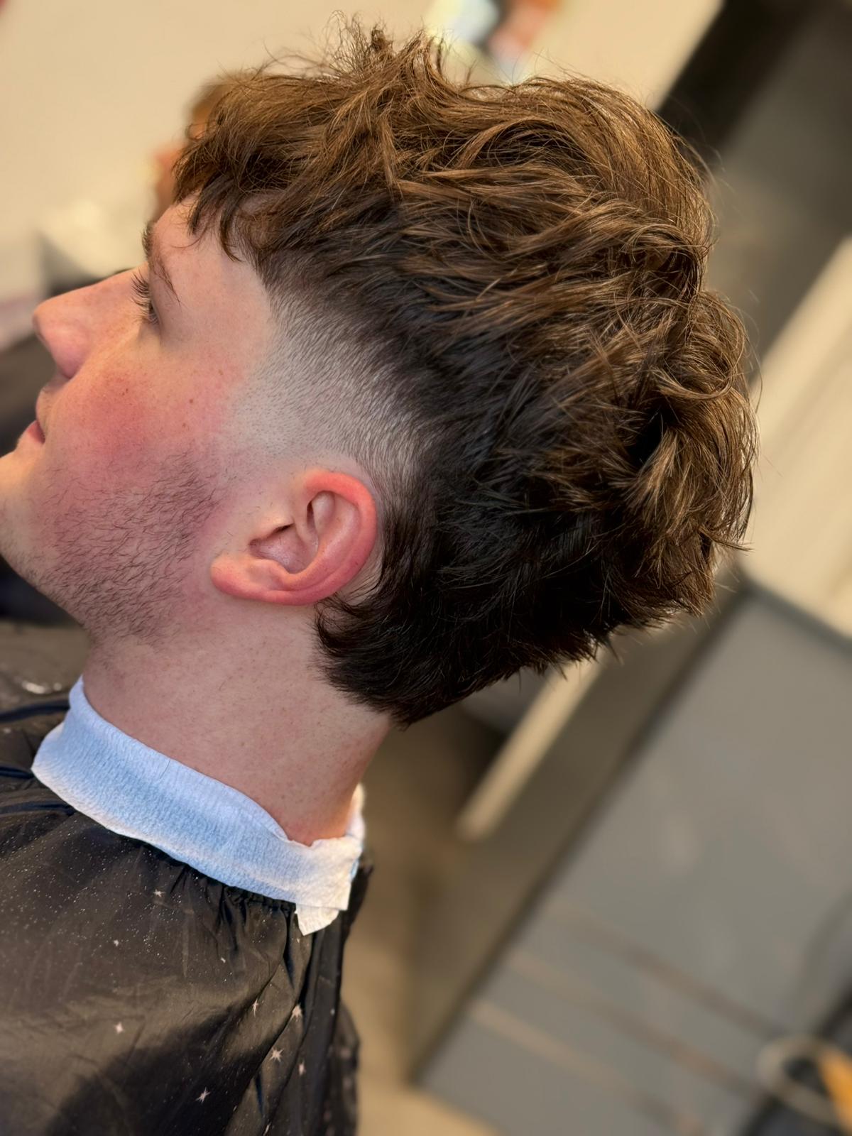 Moderní střih s vlnitými vlasy a čistým fade na stranách